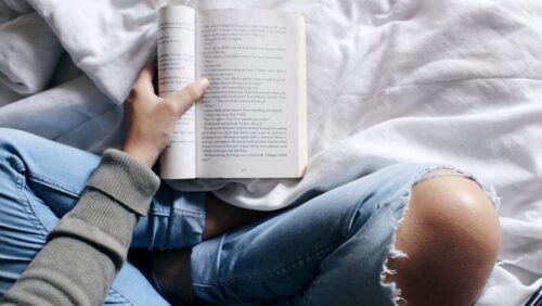 person-sitting-crosslegged-in-bed-and-reading